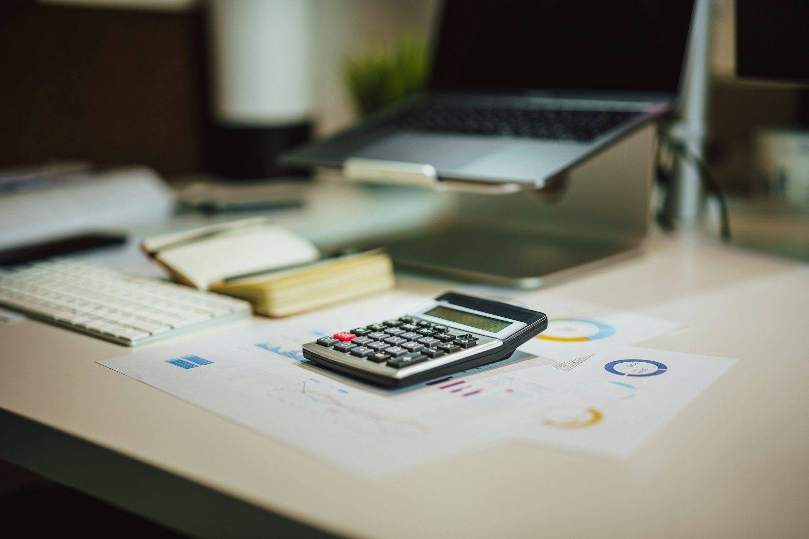A calculator on printed financial charts beside a keyboard
